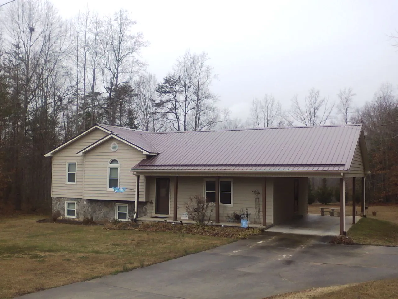 Burgundy metal roof on a tan split level home with an attached carport in Lewisville