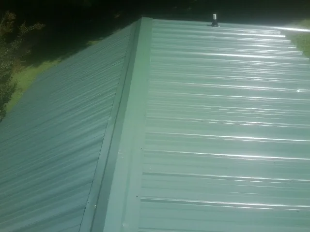 New green metal panels meeting at the ridge of a roof — Flat Roof Repair work by our crew in Lewisville